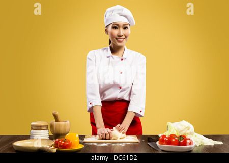 Asian female chef cooking pizza dough