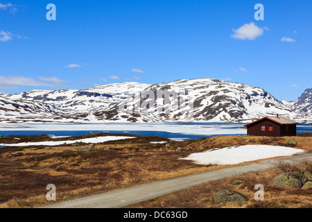 Holiday cabin by Lake Kjelavatn with ice and snow in high moorland in early summer. Hardanger, Telemark, Norway, Scandinavia Stock Photo