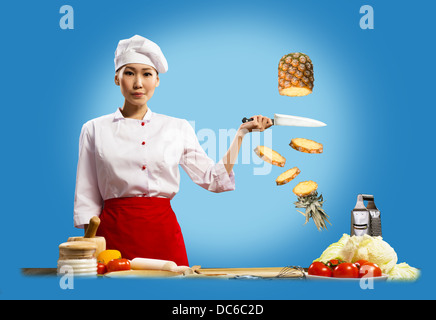Asian female chef cuts pineapple Stock Photo