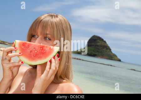 A woman holds up a slice of watermelon in front of her face. Stock Photo