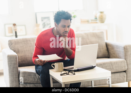 Man sitting on sofa and using laptop Stock Photo