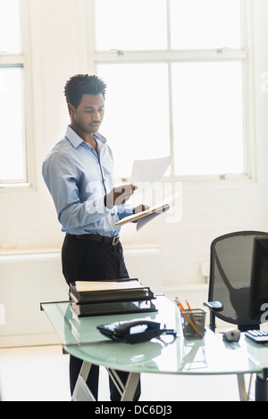 Businessman reading documents in office Stock Photo
