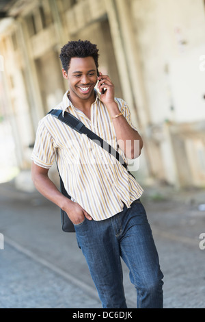 Man walking on street and talking on cell phone Stock Photo