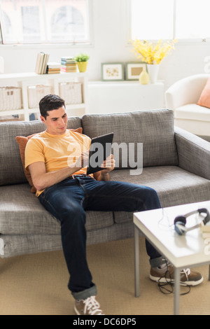 Man sitting on sofa and using digital tablet Stock Photo