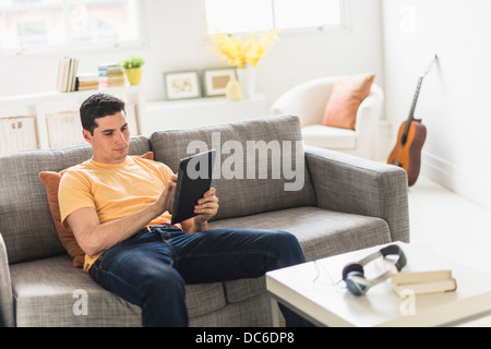 Man sitting on sofa and using digital tablet Stock Photo