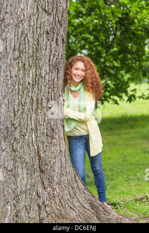 Woman leaning on tree in park Stock Photo