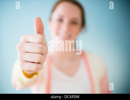 Teenage girl (14-15) showing thumb up, studio shot Stock Photo