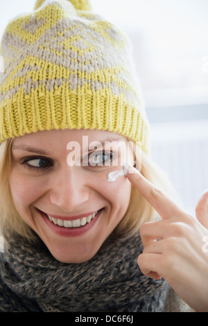 Portrait of smiling woman applying face cream Stock Photo