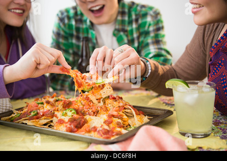 Young women and man eating nachos with melted cheese Stock Photo