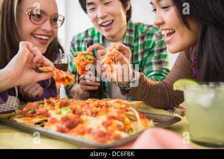 Young women and man eating nachos with melted cheese Stock Photo