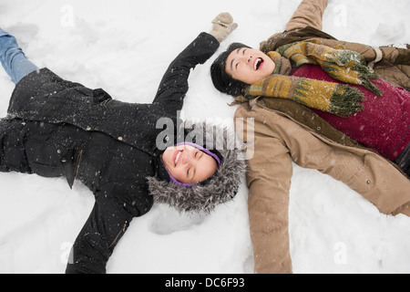 Two young people making snow angels Stock Photo