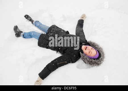 Young woman making snow angel Stock Photo