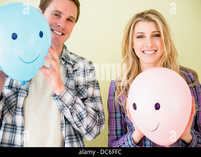 Studio shot of couple holding balloons with smiley faces Stock Photo