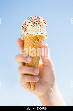 Girl (8-9) holding ice cream against blue sky