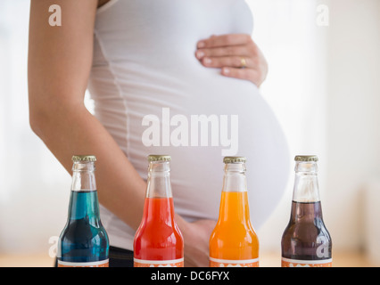 Mid section of pregnant woman, soda bottles in front Stock Photo