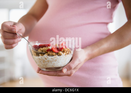 Mid section of pregnant woman holding bowl with granola Stock Photo