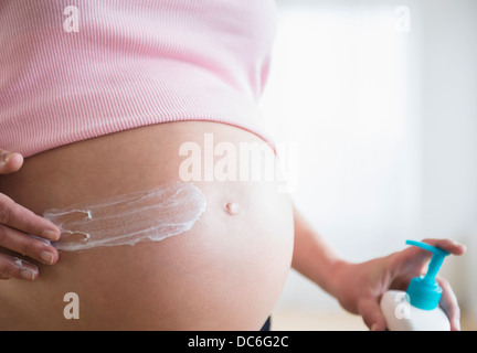 Mid section of pregnant woman applying moisturizer on her belly Stock Photo