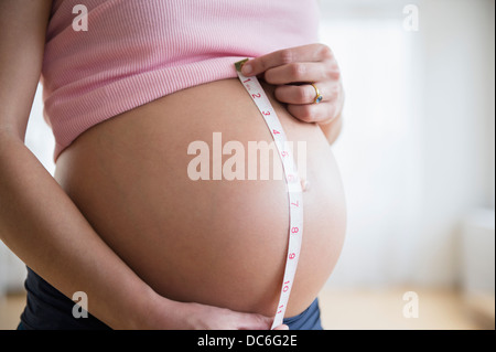 Mid section of pregnant woman measuring her belly Stock Photo