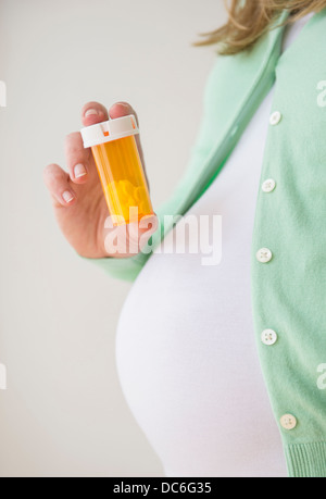 Mid section of pregnant woman holding pill bottle Stock Photo