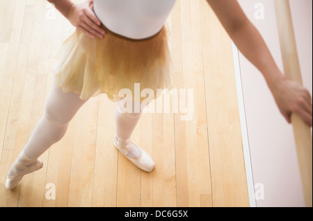 Portrait of teenage (16-17) ballet dancer standing in ballet position at barre Stock Photo