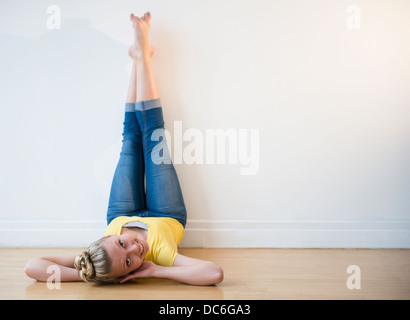 Portrait of teenage (16-17) ballerina lying down with feet up against wall Stock Photo