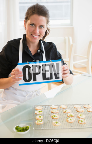 Portrait of woman holding open sign Stock Photo