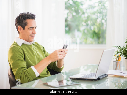 Portrait of man using mobile phone at desk Stock Photo