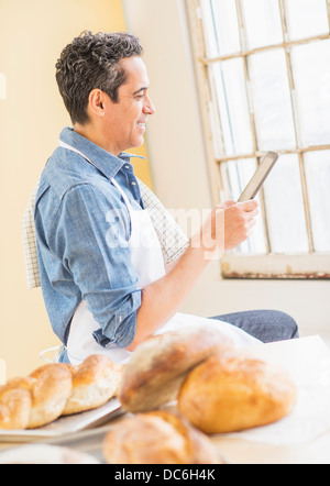 Side view of baker using digital tablet Stock Photo