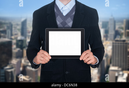 Handsome businessman in black suit showing modern digital tablet with blank screen. Isolated on cityscape background Stock Photo