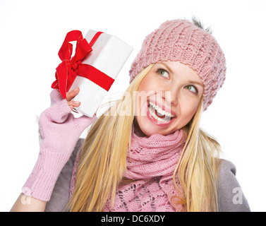 Smiling teenager girl in winter hat and scarf shaking presenting box Stock Photo