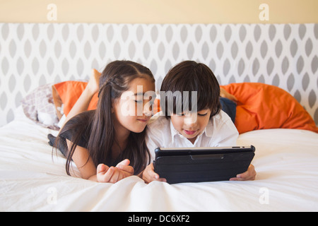 Siblings (8-9) using digital tablet in bedroom Stock Photo