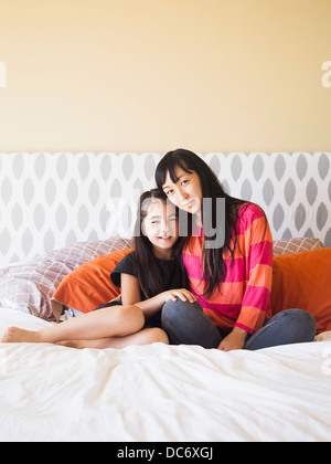Mother with daughter (8-9) sitting on bed Stock Photo