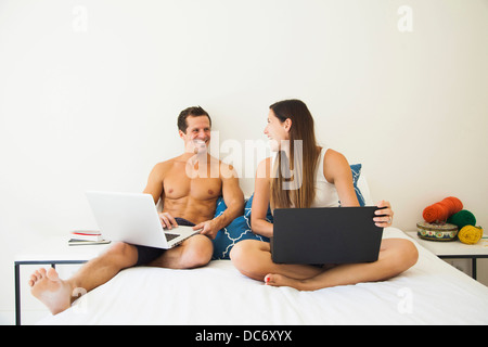 Couple lying on bed with laptop Stock Photo
