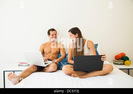 Couple lying on bed with laptop Stock Photo