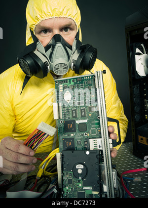 Man dealing with computer virus (figurative) or toxic chemicals heavy metals with computer and various hardware components Stock Photo