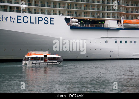 A tender moves visitors to and from the Celebrity Eclipse cruise ship that is moored in the fjord at Geiranger Norway. Stock Photo