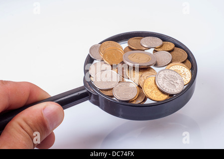 Magnifying glass on the stack of coins on out of focus green tree