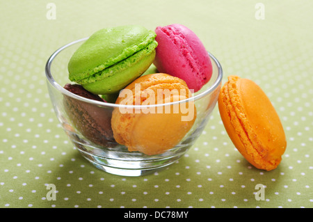 Colorful macaroons in glass bowl over green background Stock Photo