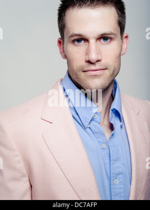 Handsome Caucasian man in his wearing baby blue shirt and pink jacket Stock Photo
