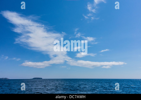 Puffy white clouds in sky create an interesting pattern off of the from sea with puffy white clouds in sky. Stock Photo