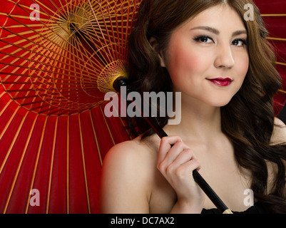 Beautiful young Japanese woman in her twenties with traditional red handmade Oil-paper umbrella WAGASA Stock Photo