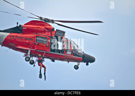 A US Coast Guard rescue swimmer is hoisted down from a HH-65C Dolphin helicopter during a training exercise August 9, 2013 in Port Republic, NJ. Stock Photo