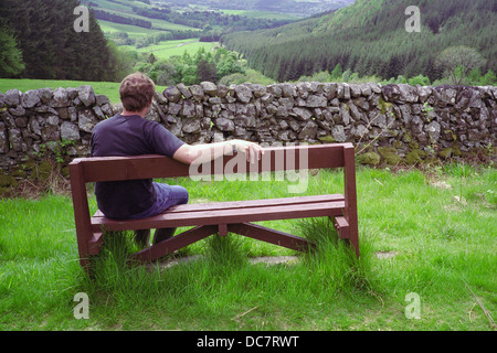Caucasian Man Sitting on a Wooden Bench Admiring View to Moffat Dale, Dumfries & Galloway, Scotland, UK MODEL RELEASED Stock Photo