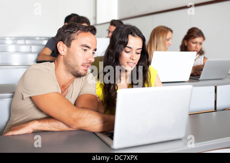 Students studying with laptops in class room Stock Photo