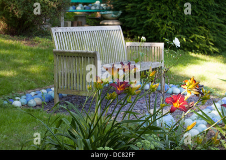 Carole Waller's garden at Bathford, Somerset, summer. Wooden bench in late afternoon sunlight Stock Photo