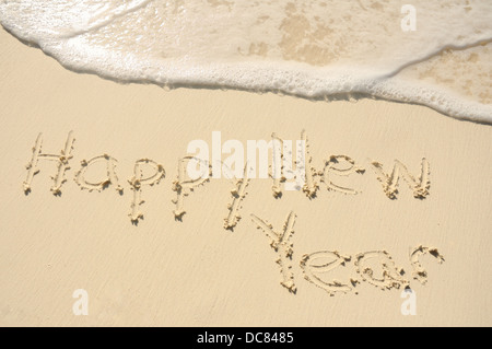 The Phrase 'Happy New Year' Written in the Sand on a Beach Stock Photo