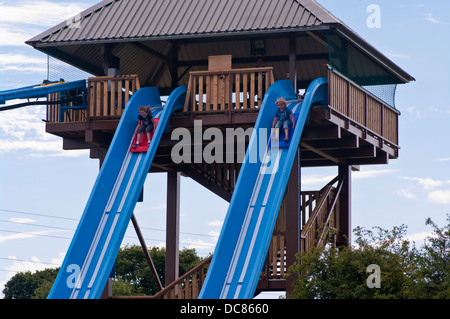 Children Sliding Down a Waterslide At Knockhatch Adventure Park Near Hailsham East Sussex UK Stock Photo