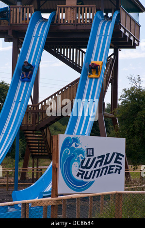 Children Sliding Down a Waterslide At Knockhatch Adventure Park Near Hailsham East Sussex UK Stock Photo