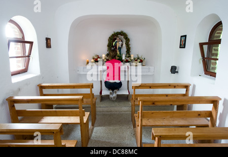 A woman is praying in a small chapel Stock Photo