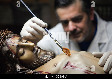 Cleaning of the face of a wooden sculpture of Christ crucified with a fan brush, Andalusia, Spain Stock Photo